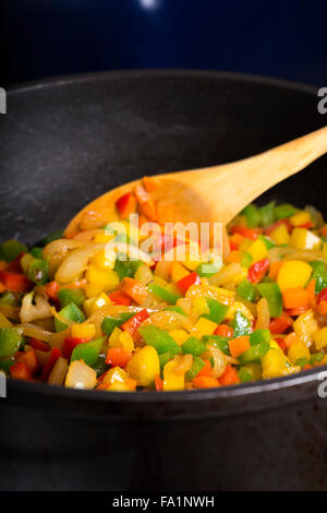 Paprika (Peperoni) gebraten mit Karotten und Zwiebeln Holzlöffel Stockfoto