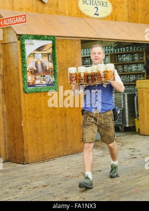 Kellner in einem traditionellen Lederhosen tragen riesige Gläser Bier Oktoberfest in München, Deutschland Stockfoto