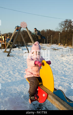 Kinder schwingen auf einer Schaukel im winter Stockfoto