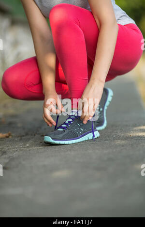 Young Sport Mädchen auf Turnschuhe Langlauf Schnürsenkel zu binden. Stockfoto