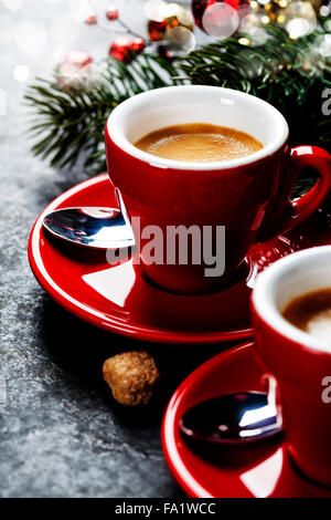 Kaffee Espresso. Rote Tassen Kaffee und Weihnachtsdekorationen auf dunklem Hintergrund Stockfoto