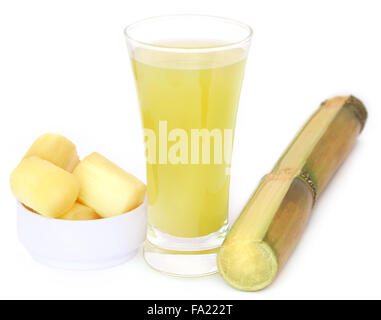 Stück von Zuckerrohr mit Saft in einem Glas Stockfoto