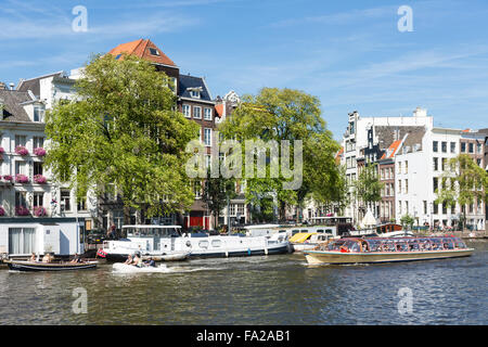 AMSTERDAM, Niederlande - AUG 06: Kanal mit erholsamen Menschen in kleinen Booten und eine vorübergehende Kreuzfahrtschiff Stockfoto