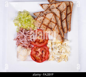 Traditionelles englisches Frühstück mit Rührei, Tomaten, Kartoffeln, Toast und frischem Salat Stockfoto