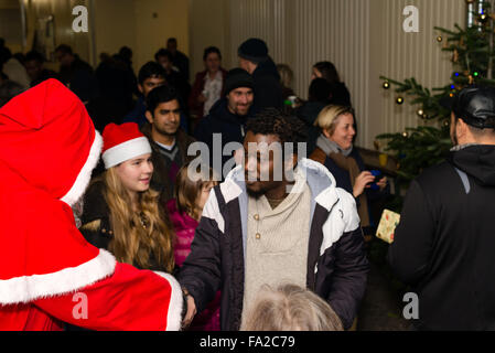 Scharnhausen, Deutschland - 20. Dezember 2015: Flüchtlinge aus Libyen, Nigeria, Afghanistan, Pakistan, Eritrea, Gambia, Togo, Algerien, Tunesien und anderen Ländern Geschenke vom Weihnachtsmann während einer Weihnachtsfeier organisiert von Freiwilligen in die Flüchtlingslager in Scharnhausen bei Stuttgart in Deutschland erhalten. Tausende von Flüchtlingen sind derzeit auf der Flucht nach Deutschland, Asyl zu beantragen, da sie durch ISIS und Kriege in ihren Heimatländern bedroht sind. Bildnachweis: franky242/Alamy Live-Nachrichten Stockfoto