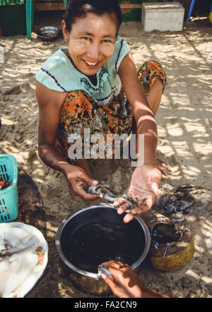 Ngwesaung oder Ngwe Hsaung, Myanmar, Birma - 20. April 2014: Frau, die frisch gefangenen Tintenfisch zubereitete. Stockfoto