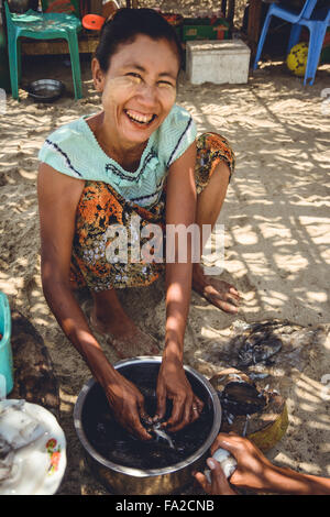 Ngwesaung oder Ngwe Hsaung, Myanmar, Birma - 20. April 2014: Frau, die frisch gefangenen Tintenfisch zubereitete. Stockfoto