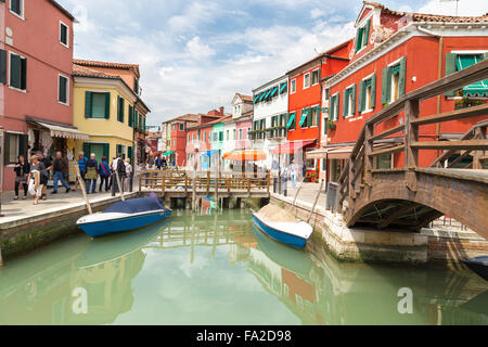 Touristen, die zu Fuß in Burano Stadtstraßen und Boote in der Lagune in der schönen Stadt von Burano Stockfoto