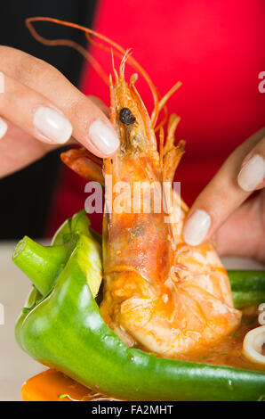 Junge Frau, die eine große leckere Garnelen essen Stockfoto