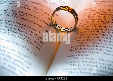 Ring mit herzförmigen Schatten auf ein offenes Buch liegend