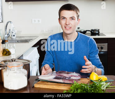 Hübscher Kerl hält roher Tintenfisch in Küche zu Hause Stockfoto