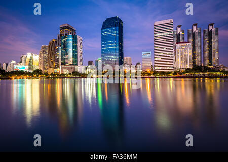 Moderne Wolkenkratzer und Lake Rajada in der Nacht, im Benjakiti Park in Bangkok, Thailand. Stockfoto