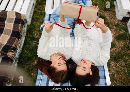 Mädchen liegen und packt ein Geschenk Stockfoto