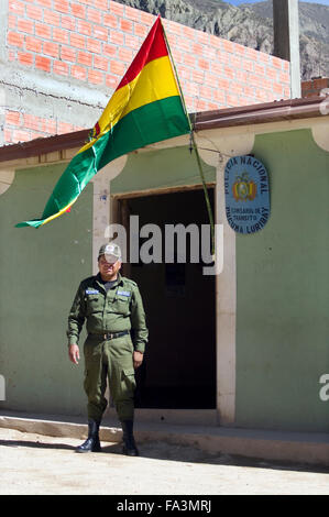 Ein Polizist steht unter einer bolivianischen Flagge vor der Polizeistation in Luribay, Bolivien, Südamerika Stockfoto