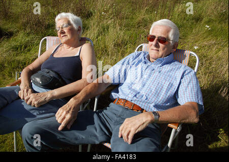 Ein paar sitzt auf einem Damm in Liegestühle die Sonne zu genießen, Stockfoto