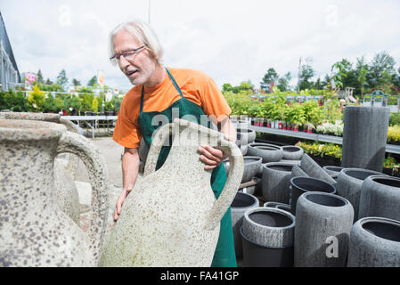 Männliche Gärtner, die Vermittlung von Keramik Töpfe im Gewächshaus, Augsburg, Bayern, Deutschland Stockfoto