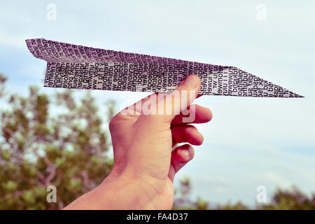 Nahaufnahme von der Hand des kaukasischen Jüngling zu einem Papierflieger mit ein bedrucktes Papier mit Unsinn Wörter, Ben gemacht werfen Sie Stockfoto