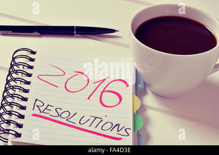 Nahaufnahme eines Notebooks mit dem Text 2016 Auflösungen geschrieben und eine Tasse Kaffee auf einem weißen Tisch Stockfoto