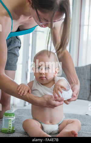 Mutter, die ihren süßen Sohn umziehen in Schlafzimmer, München, Bayern, Deutschland Stockfoto