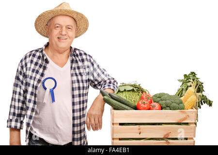 Reifen Bauer mit einem Award-Abzeichen auf seinem Hemd, stützte sich auf eine Kiste voll mit Gemüse isoliert auf weißem Hintergrund Stockfoto