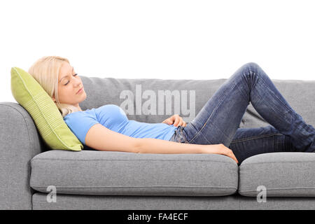 Junge, blonde Frau schlafen auf eine graue couch isolierten auf weißen Hintergrund Stockfoto