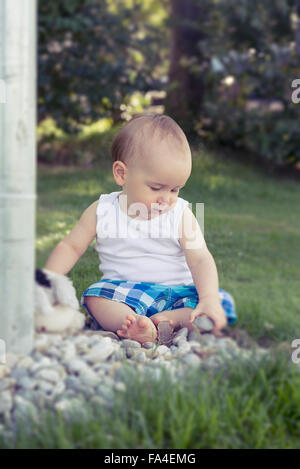 Baby Junge spielt mit Kieselsteinen in Rasen, München, Bayern, Deutschland Stockfoto