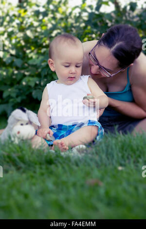 Baby Junge und seine Mutter spielt mit Kieselsteinen in Rasen, München, Bayern, Deutschland Stockfoto