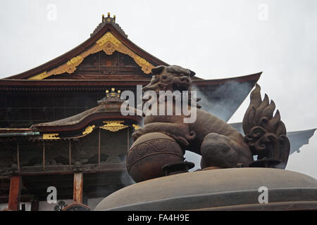 Eine Löwenstatue auf die Weihrauch-Brenner außerhalb der Hon-Do-Haupthalle Zenko-Ji buddhistische Tempel, Nagano, Japan, im Herbst Stockfoto