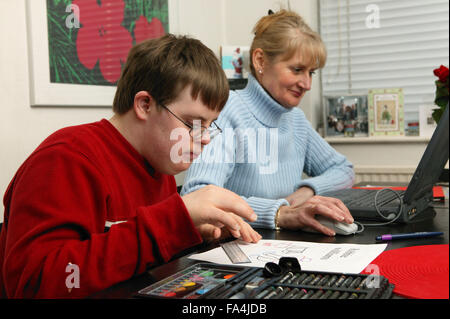 Alleinerziehende Mutter, die an einem Computer arbeiten, während ihr Sohn seine Hausaufgaben macht, Stockfoto