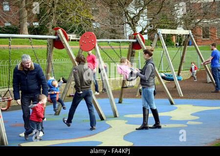 Eltern und Kinder auf der Schaukel im Park spielen. Stockfoto