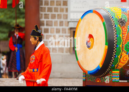 Große traditionelle koreanische Schlagzeuger in roten Kostümen, die darauf warten, eine alte Trommel im Deoksugung Palast bang Stockfoto