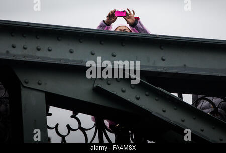 Ein Tourist nimmt ein Foto, wie sie auf die Brücke "Eiserner Steg" (lit. Eisernen Steg) steht die Mains in Frankfurt/Main, Deutschland, 21. Dezember 2015 durchquert. Foto: Frank Rumpenhorst/dpa Stockfoto