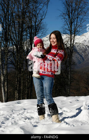 Mutter und Tochter spielen im Schnee im Wald an einem sonnigen Tag im winter Stockfoto