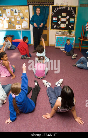 Lehrer im Klassenzimmer, im Gespräch mit der Gruppe von Schulkindern stehend, Stockfoto