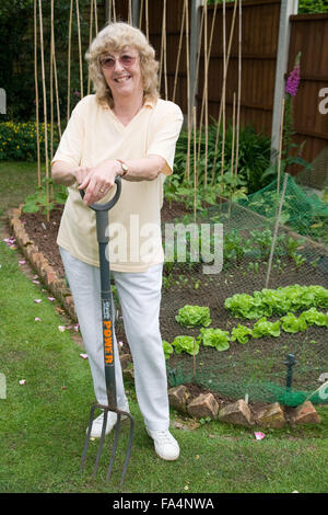Frau ruht auf ihre Gabel durch den Gemüsegarten, Stockfoto