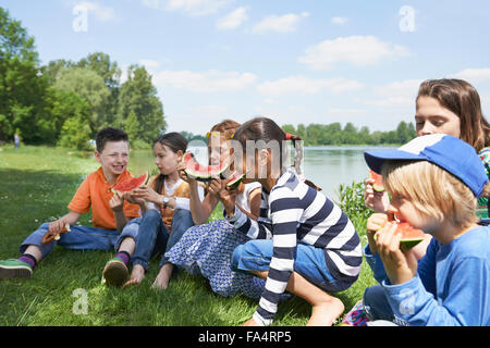 Kinder freuen sich über Scheiben Wassermelone bei Picknick, München, Bayern, Deutschland Stockfoto