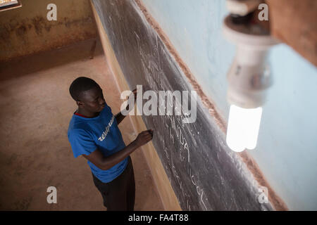 Ein Student schreibt an die Tafel eines Klassenzimmers von Solarstrom in Nyarubanda Dorf, Kigoma Region, Westen Tansanias beleuchtet. Stockfoto