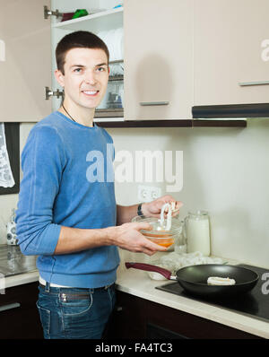 Glücklicher Mann Kochen Braten Tintenfisch Ringe in Teig in Küche Stockfoto