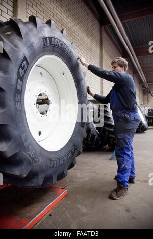 Lehrling Monteur ändern ein Traktorreifen. Stockfoto