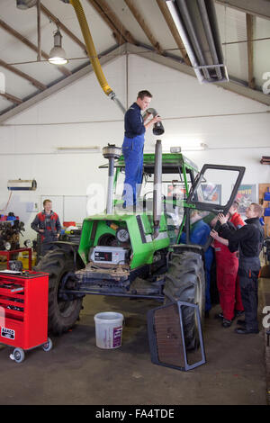 Praktische Ausbildung an einem Traktor. Lehrling legt eine Abgas-Absaugung. Stockfoto