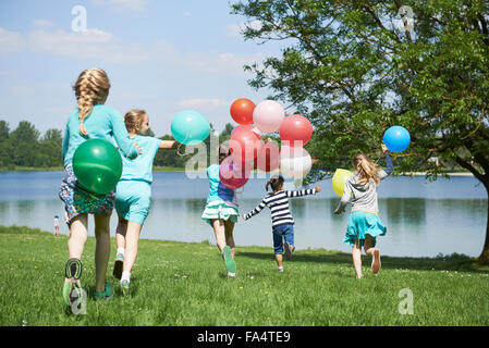 Rückansicht des Mädchen laufen im Park mit Luftballons, See Karlsfeld, München, Bayern, Deutschland Stockfoto