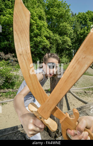 Zwei Mädchen, so zu tun als Piraten kämpfen mit Schwertern in Abenteuer Spielplatz, Bayern, Deutschland Stockfoto