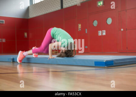 Mädchen tun Purzelbaum auf Gymnastikmatte in Sporthalle, München, Bayern, Deutschland Stockfoto