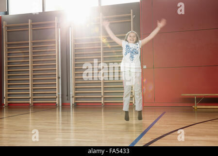 Fröhliches kleines Mädchen springen in Sporthalle, München, Bayern, Deutschland Stockfoto