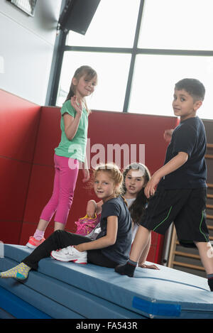 Kinder spielen auf einem Stapel Sportmatten in Sporthalle, München, Bayern, Deutschland Stockfoto