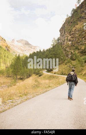 Rückansicht des Reifen Wanderer zu Fuß auf Mountain Road, Österreichische Alpen, Kärnten, Österreich Stockfoto