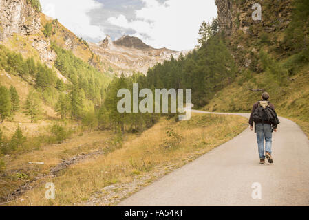 Rückansicht des Reifen Wanderer zu Fuß auf der Straße, Österreichische Alpen, Kärnten, Österreich Stockfoto