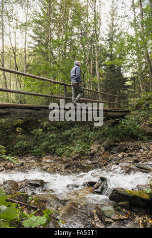 Reife Wanderer Kreuzung Fußgängerbrücke in Wald, Alpen, Kärnten, Österreich Stockfoto