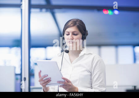 Geschäftsfrau mit Headset und Lesepapier, Freiburg im Breisgau, Baden-Württemberg Stockfoto