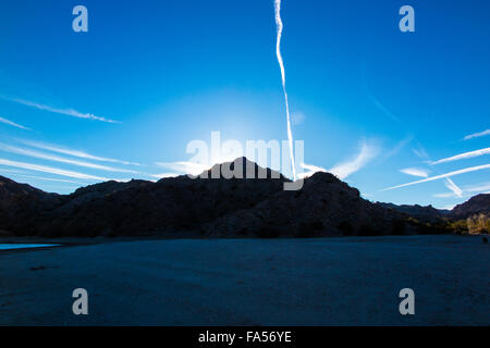 Die Sonne geht am Lake Mohave in der Wüste von Nevada mit einem Himmel voller Kondensstreifen von vorbeifahrenden Düsen. Stockfoto